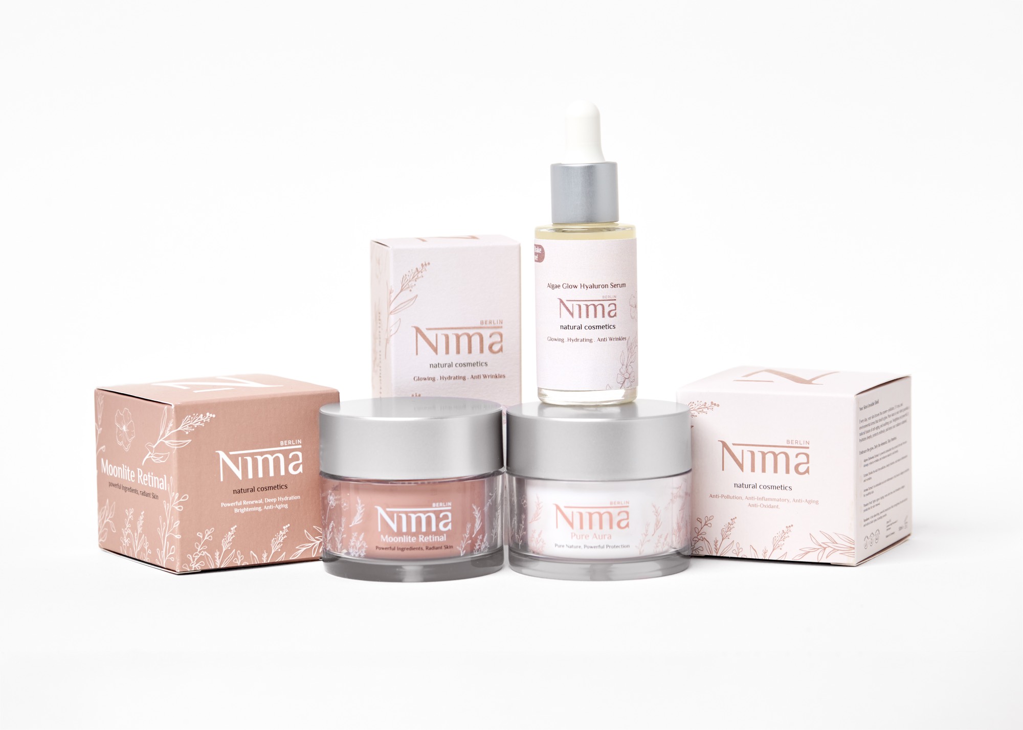 NIMA-Pflegeprodukte mit Tiegeln, Serumflasche und Verpackungen auf hellem Hintergrund