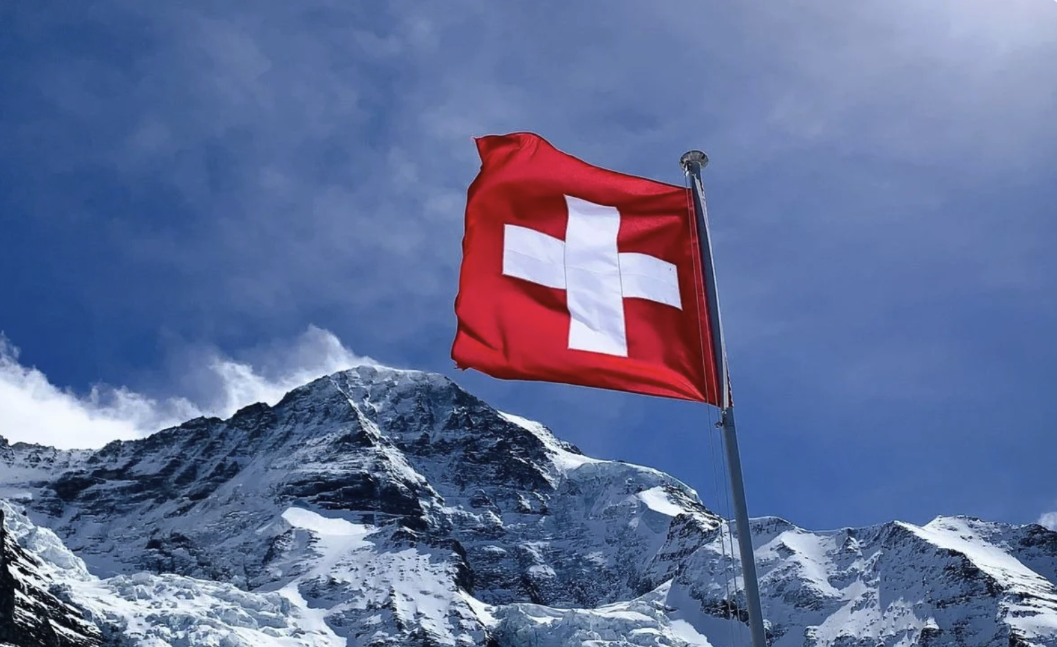 Schweizer Flagge vor schneebedeckten Bergen